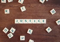 Scrabble letters on the table, with the center letters spelling out 'JUSTICE'