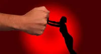 Silhouette of a woman pushing back on the photo of a giant fist coming towards her