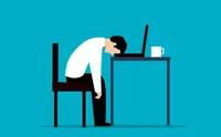 Man sitting at a table with his head slumped down and resting on the keyboard of a laptop