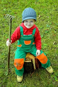 Picture of a child dressed as a farmer and holding a small rake