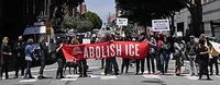Protestors carrying a sign saying 'Abolish ICE'