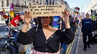 A woman in a line of protesters holds a sign reading 'Fuck white supremacy! If you disagree...fuck you too.'