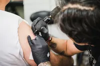 Picture of a tattoo artist applying a tattoo to a customer's arm