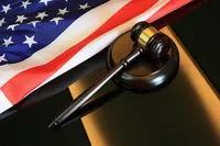 Picture of a gavel on a desk next to an American flag